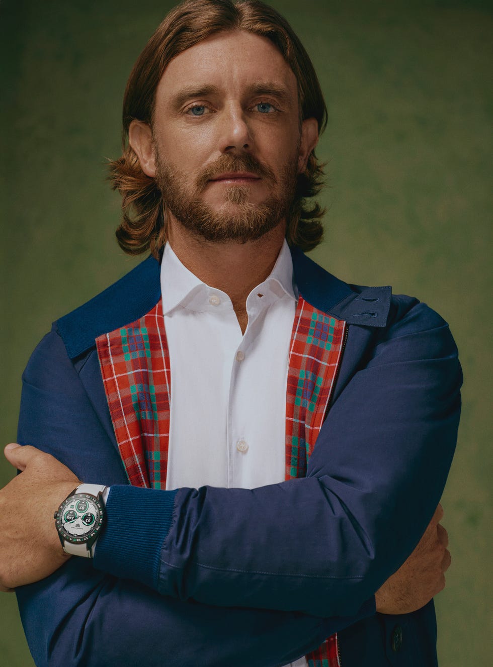 Man with folded arms wearing a blue jacket and patterned lining, visible wristwatch