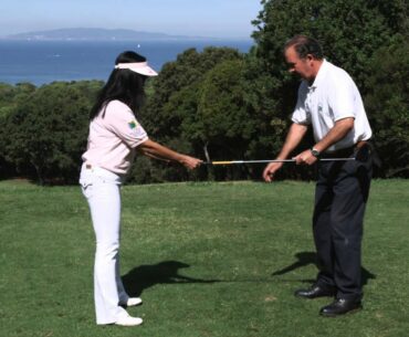 Golf trainer showing woman propper stance.