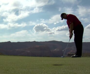 man puts golf ball into hole