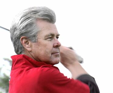 Golfer's face as he tees off then laughs.