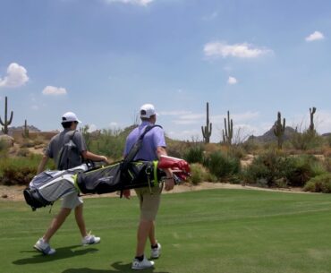 two golfers with golf bags on a desert golf course