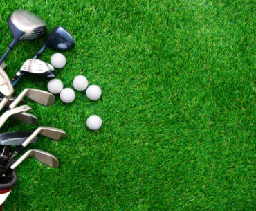 Golf ball and golf club in bag on green grass