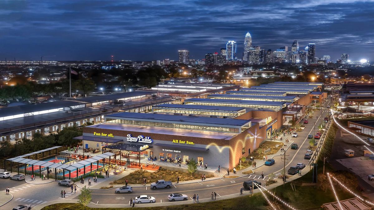 An aerial view of a vast pickle ball complex stretching down the block, with the view of the Charlotte skyline in the background. 