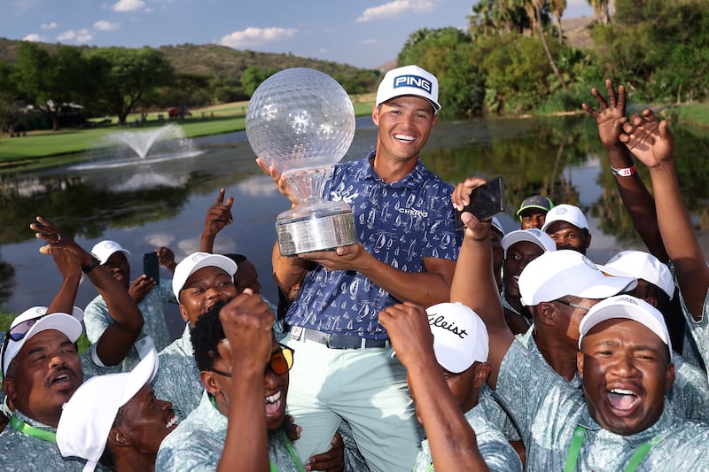 Johannes Veerman of the United States holds the trophy as he celebrates victory with ground staff on the 18th green on day four of the Nedbank Golf Challenge. Photograph: Warren Little/Getty
