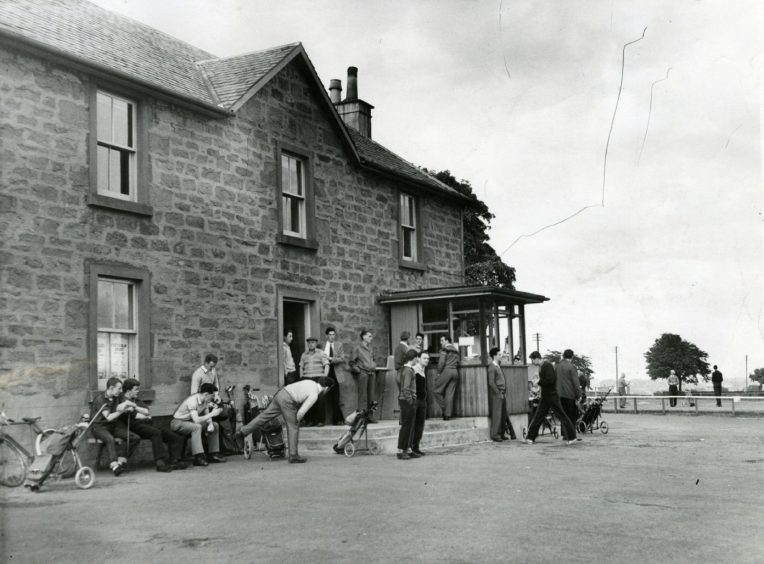 Players stand outside a building while waiting to tee off from Caird Park in 1961.