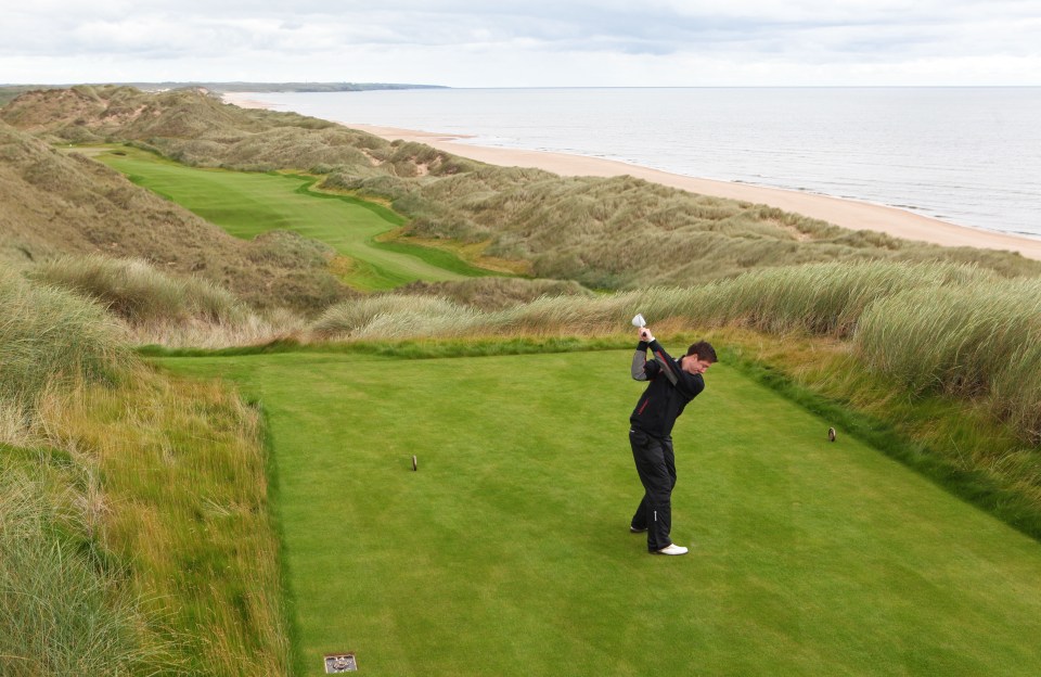 Golfer teeing off on a coastal golf course.
