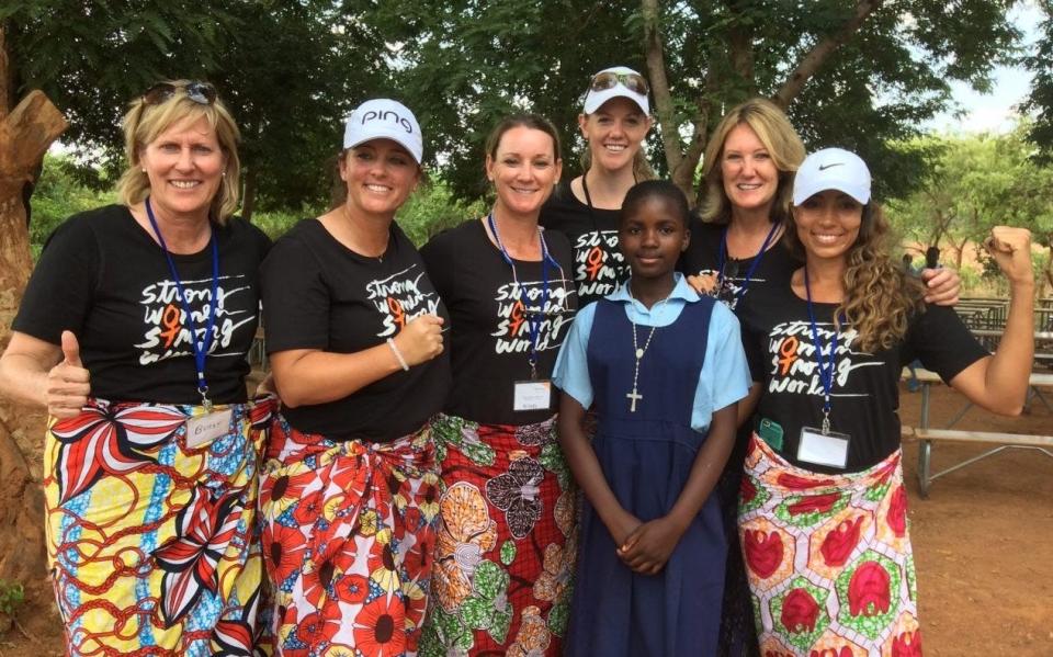 Betsy King, Kendall Dye, Kristy McPherson, Amy Olson, Debbie Quesada and Cheyenne Woods pose with a local young girl on a trip to Africa.