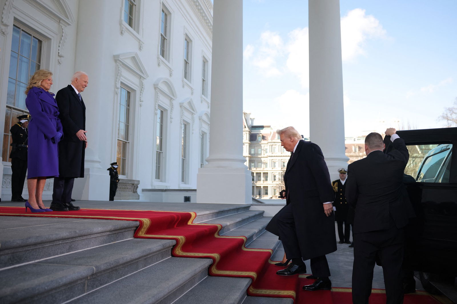 Donald Trump walking up the steps of the White House towards Joe and Jill Biden
