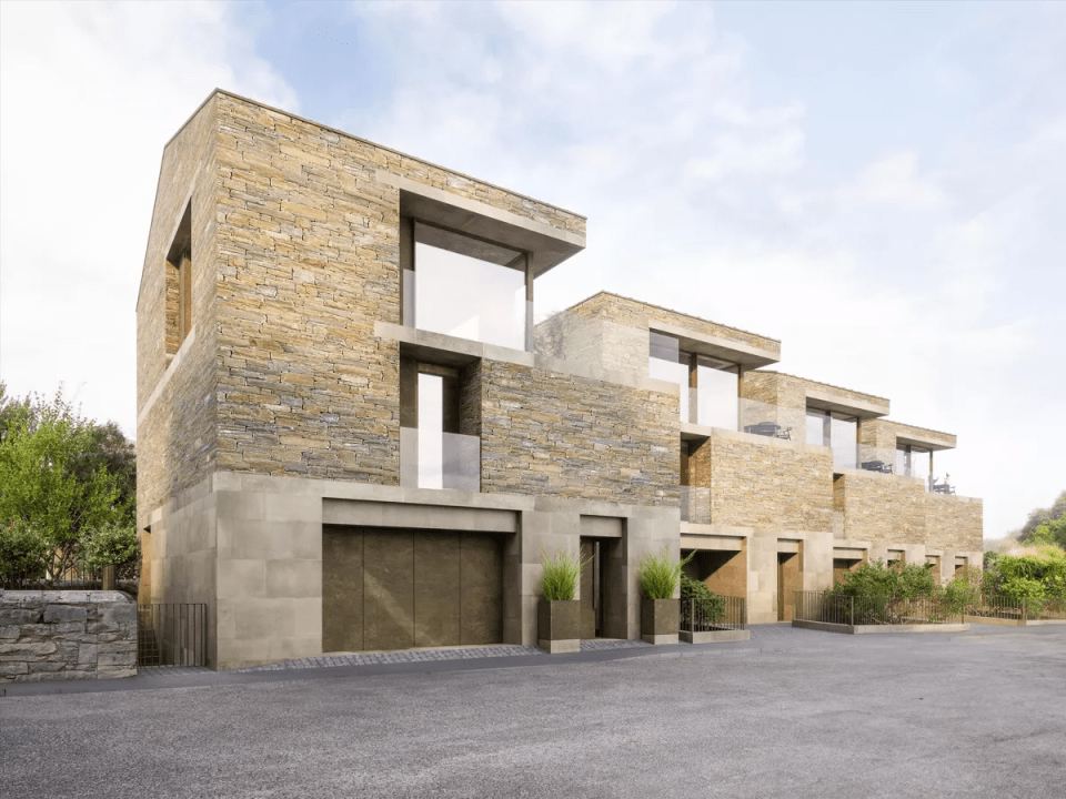 Illustration of townhouses with stone exteriors and attached garages.