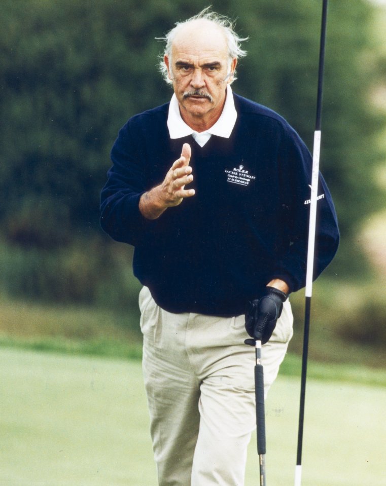 Sean Connery lines up a putt during a golf tournament.