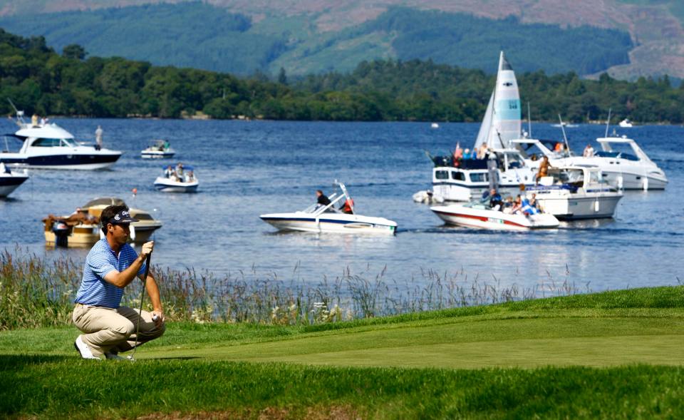 Golfer lining up a putt on a green overlooking a lake with boats.