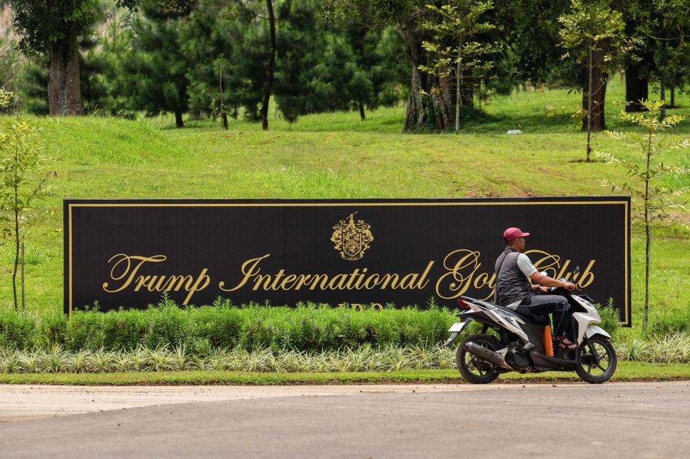 This photo taken on March 13, 2025 shows a man riding his motorcycle past the logo of the Trump International Golf Club, Lido, an 18-hole golf course spread across a 700-meter-high plateau, designed by renowned South African professional golfer and course architect Ernie Els, at the club's entrance in Bogor, West Java. — AFP pic