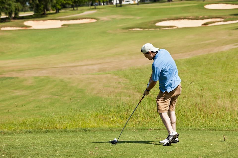 Young male golfer taking a swing on the tee box on a Florida golf course.