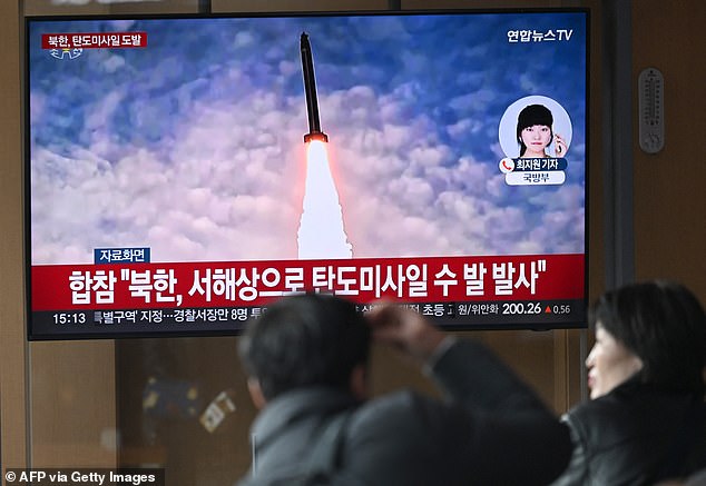 People watch a television screen showing a news broadcast with file footage of a North Korean missile test, at a train station in Seoul on March 10, 2025