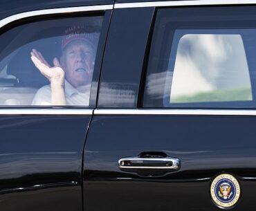Donald Trump waves from his limousine as he leaves the golf course on Sunday afternoon