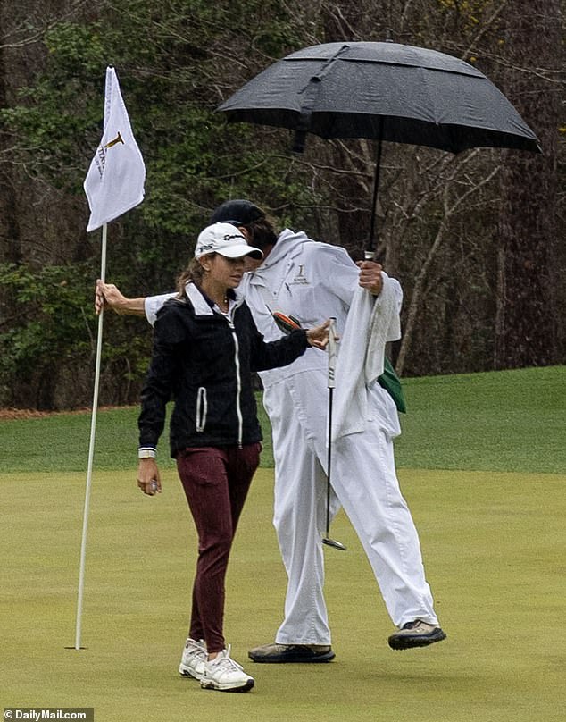 Kai's caddy holds her umbrella as she struggled to battle back into contention in the rain