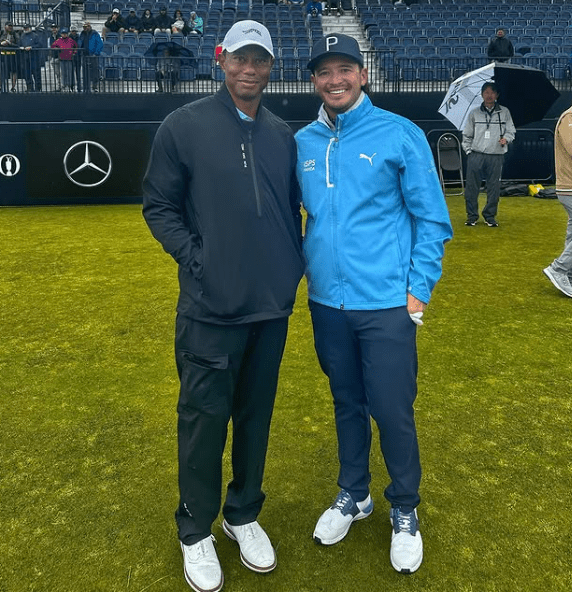 Tiger Woods and another man standing on a golf course.