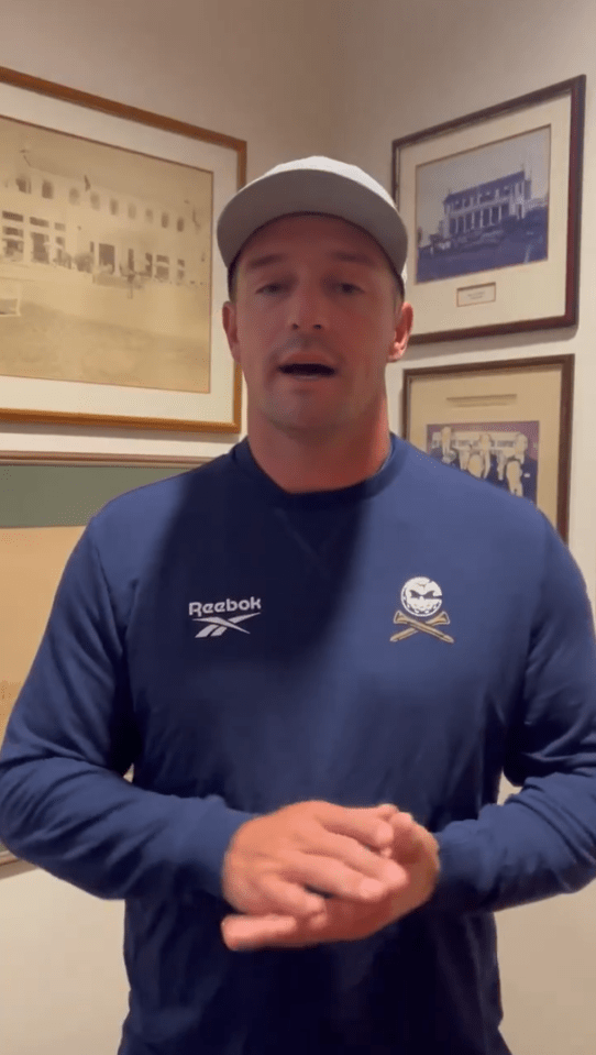 Man in Reebok sweatshirt speaking in front of framed photos.