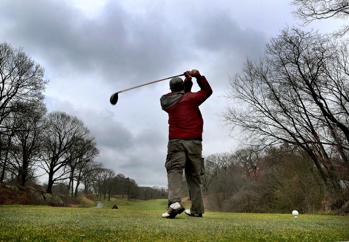 A golfer at the George Wright Golf Course in Hyde Park drives the ball under threatening skies after a rainstorm in April 2018.