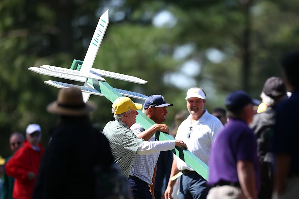 Bryson DeChambeau carries a directional sign while preparing to play his second shot on the 13th hole from the 14th fairway during the second round of the 2024 Masters Tournament at Augusta National Golf Club.