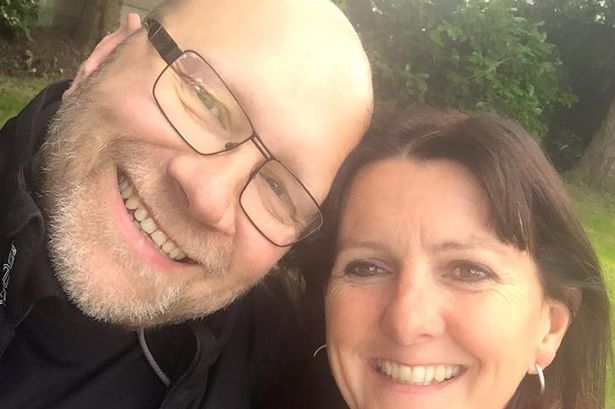 An selfie showing a bald man wearing glasses and dark-haired woman.
