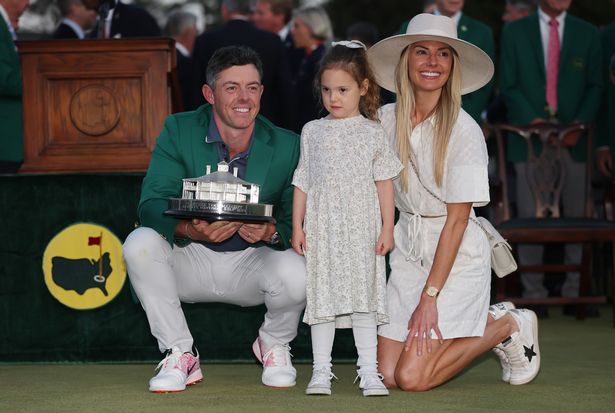 Rory McIlroy of Northern Ireland poses with daughter Poppy and wife Erica Stoll holding the Masters trophy during the Green Jacket Ceremony after winning the 2025 Masters Tournament 
