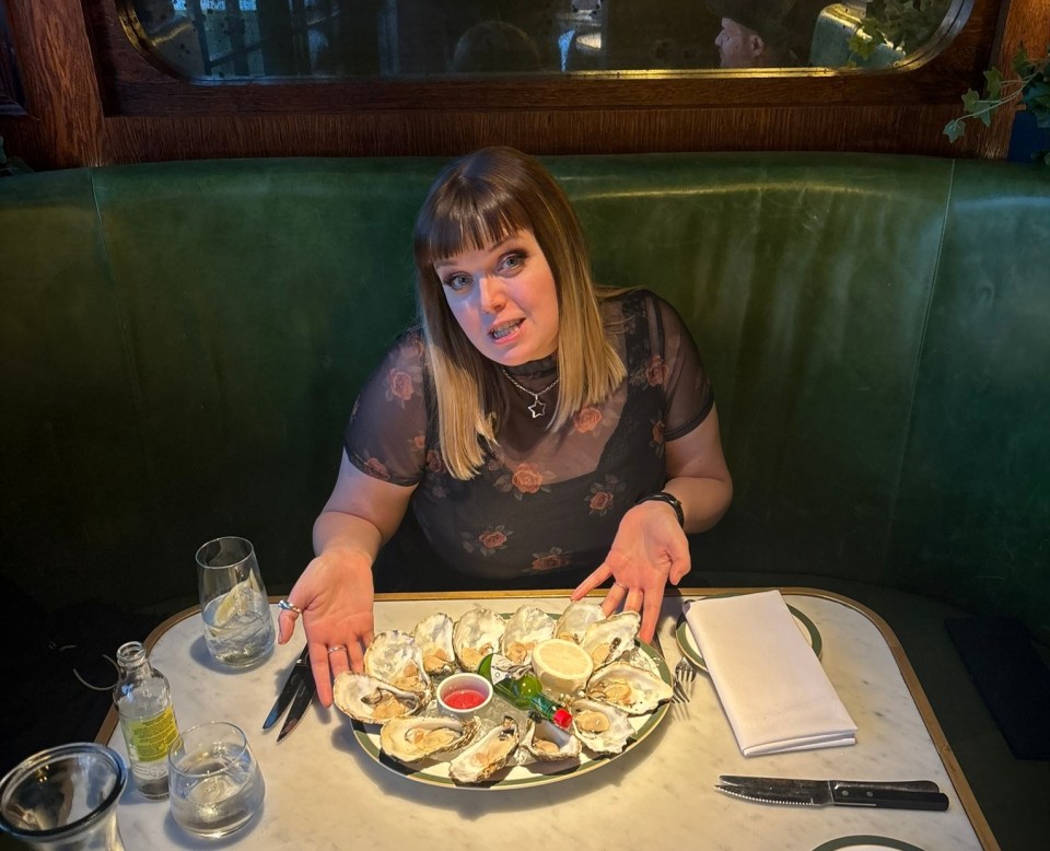 Woman sitting at a table with a plate of oysters.