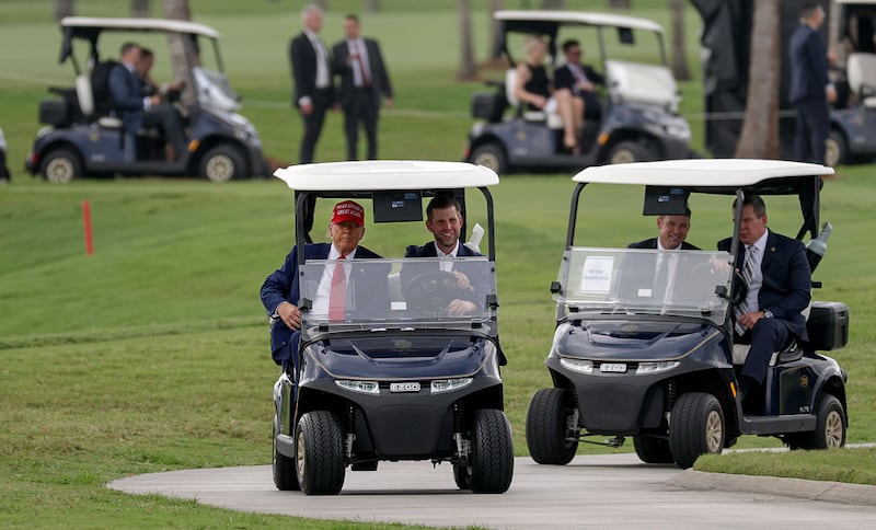 President Donald Trump and his son, Eric Trump, drive in a golf cart after he arrived on Marine One at the LIV Golf tournament being held at his Trump National Doral Golf Club on April 03, 2025 in Doral, Florida.