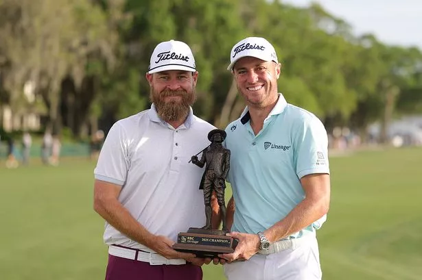 Justin Thomas of the United States poses with the trophy and caddie, Joe Greiner
