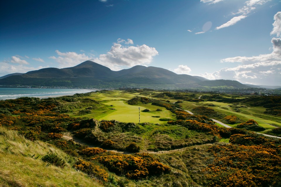 Aerial view of a golf course with mountains in the background.