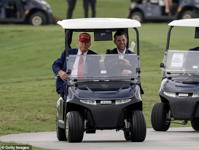 President Donald Trump and his son, Eric, drive in a golf cart after he arrived on Marine One at the LIV Golf tournament being held at his Trump National Doral Golf Club on Thursday