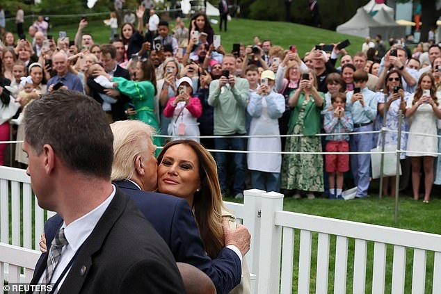 President Donald Trump (left) gives a kiss to first lady Melania Trump (right) during the White House's Easter Egg Roll on Monday