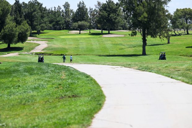 Golfers walk through the El Prado Golf Course on Tuesday,...
