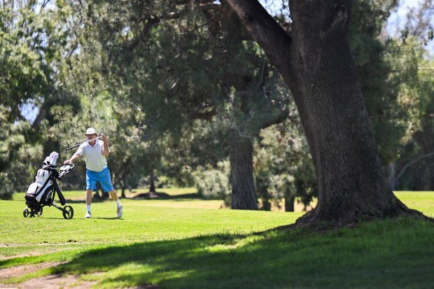 A golfer pulls a club from his bag as he...