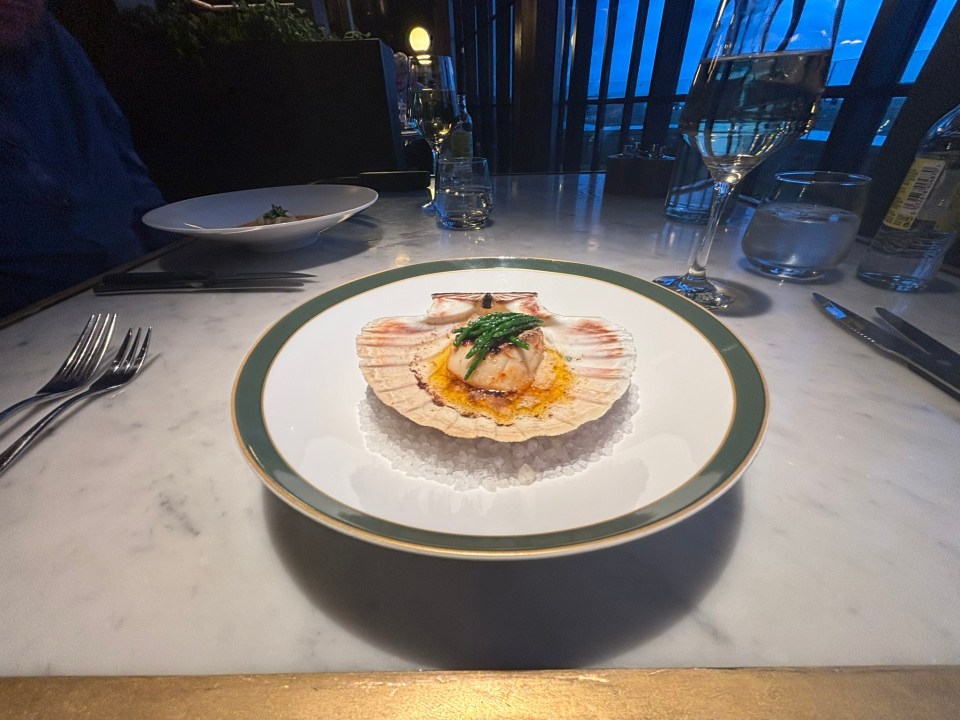 Seared scallop on the half shell with asparagus, served on a bed of salt.