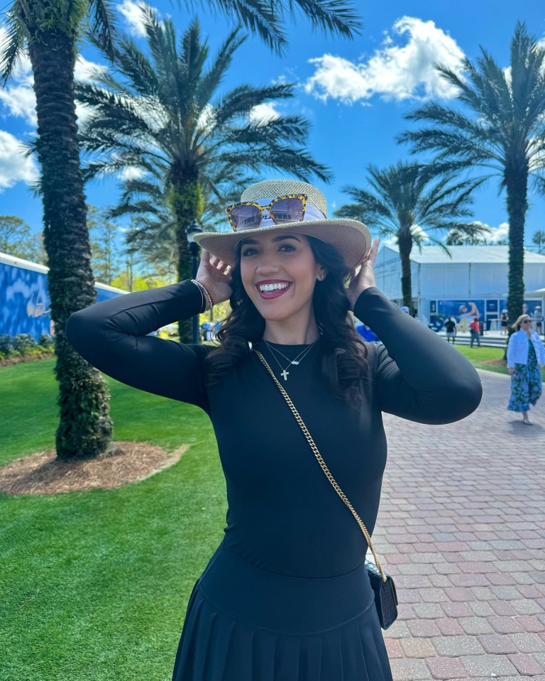 Woman in black dress and hat at a golf tournament.