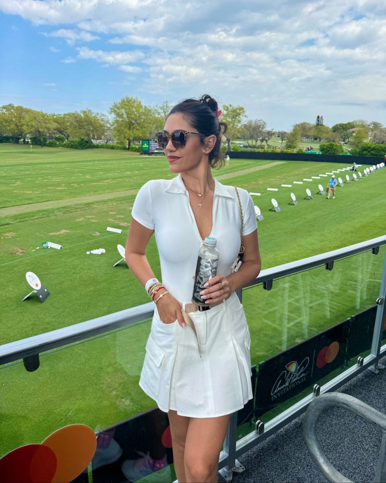 Woman in white outfit at a golf course.
