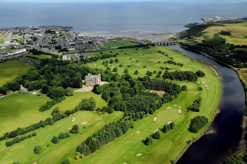 Aerial view of a castle on a golf course by the sea.