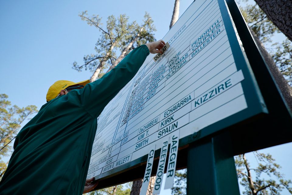 A course worker places players names and tee times on a board during a practice round