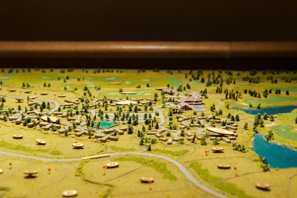 A mini diagram of a golf course with trees and bodies of water around it