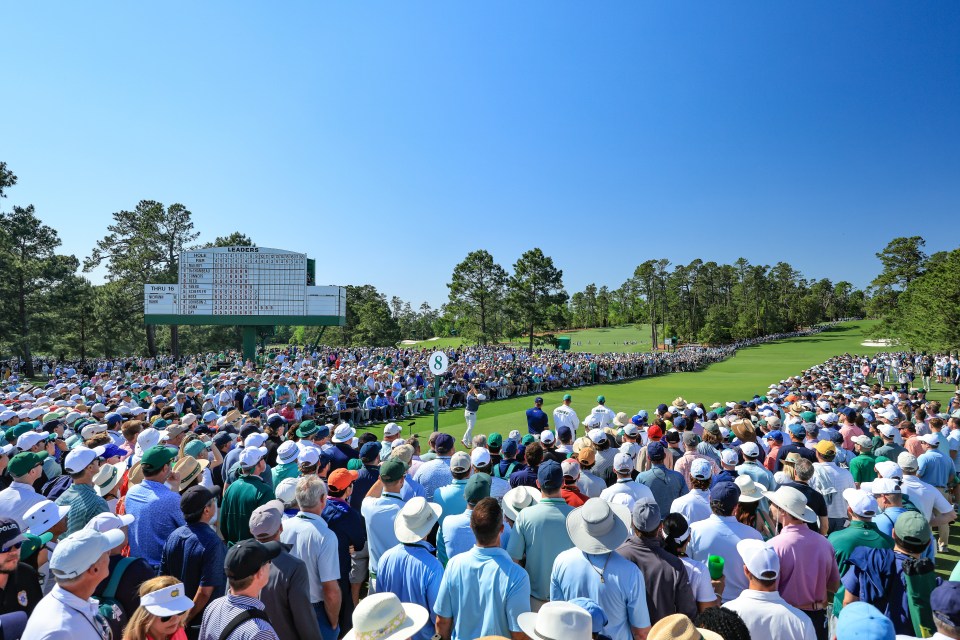 Rory McIlroy teeing off at the Masters Tournament, watched by a large crowd.