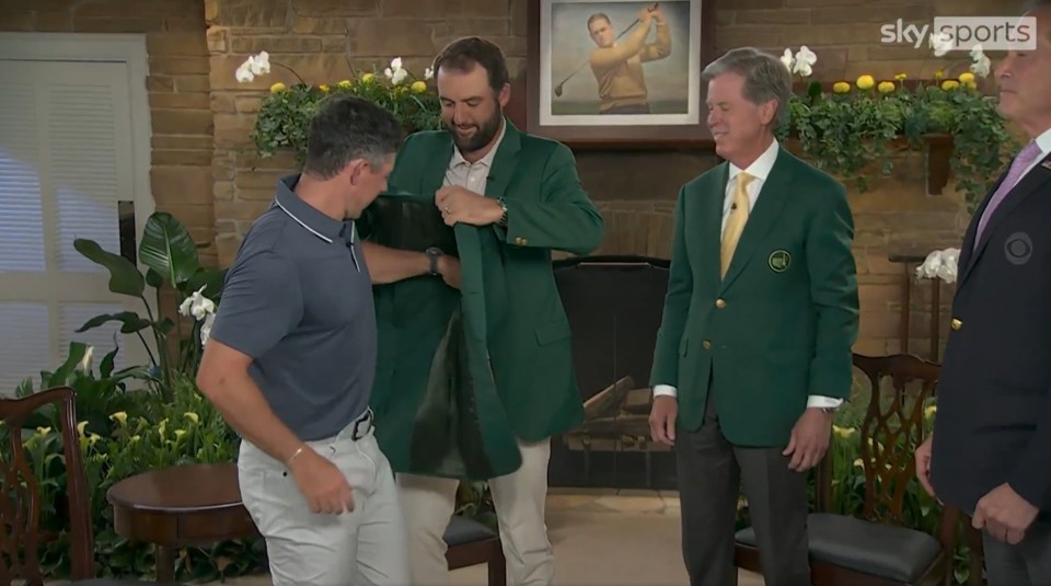 Scottie Scheffler helping Rory McIlroy put on the green jacket.