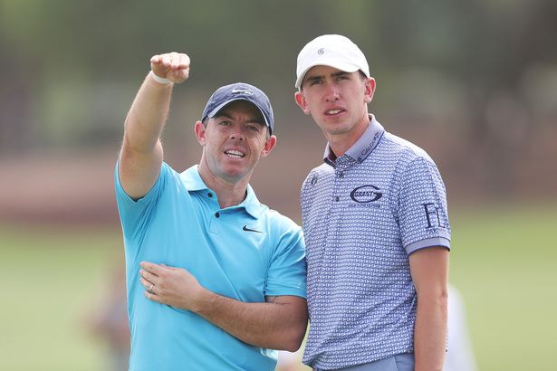 Rory McIlroy of Northern Ireland interacts with Tom McKibbin of Northern Ireland.