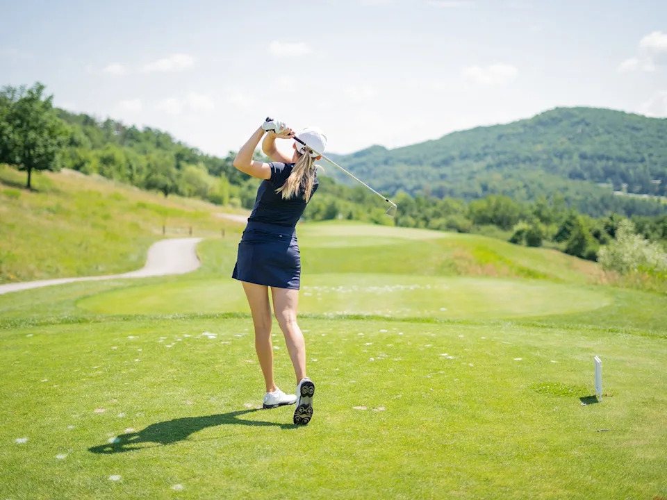 A woman teeing off at a golf course.