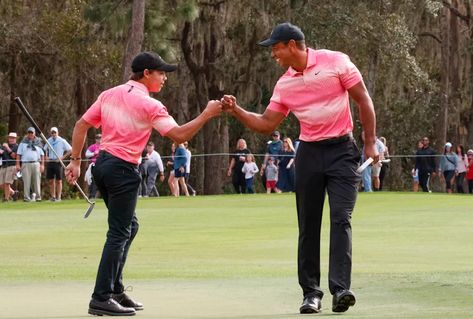 Charlie Woods and father Tiger Woods fist bump after a birdie on the ninth hole during the first round of the PNC Championship at Ritz Carlton Golf Club Grande Lakes Orlando Course.