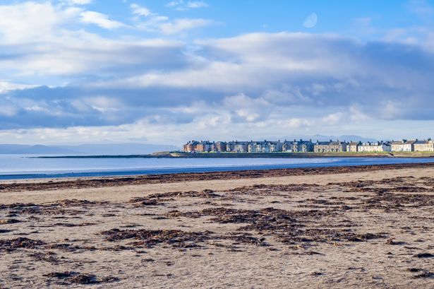 Troon from the South Bay Shore Line looking over the sand to Portland Terrace with lots of seaweed washed up onto the sandy bay.