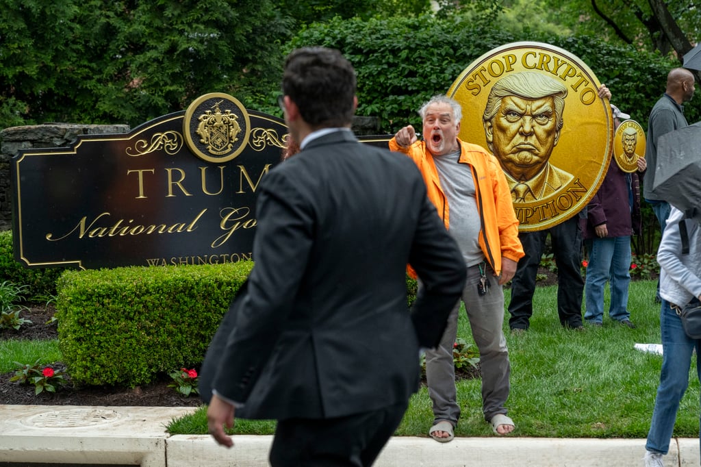 An activist calls out an attendee of an exclusive dinner at Donald Trump’s luxury golf club. Photo: AP