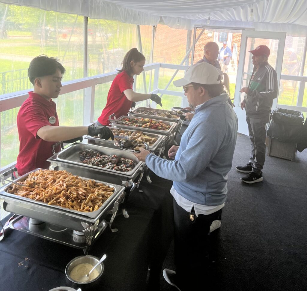 12:30 members grabbing a bite and engaging in conversation post golf. Photo by Wayne Daren Schneiderman