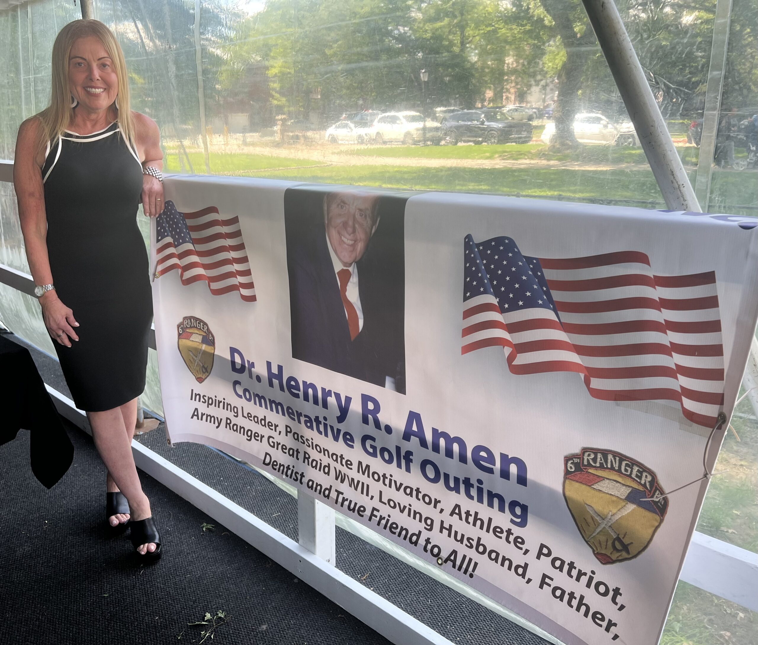 12:30 Club member Doreen Amen alongside a banner of her father, former President Dr. Henry Amen. Photo by Wayne Daren Schneiderman