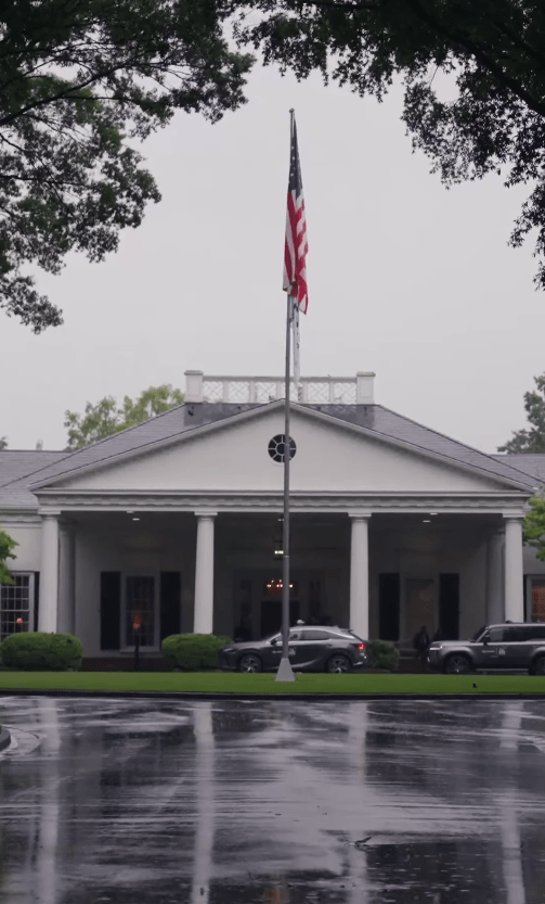 White building with columns and an American flag in front.